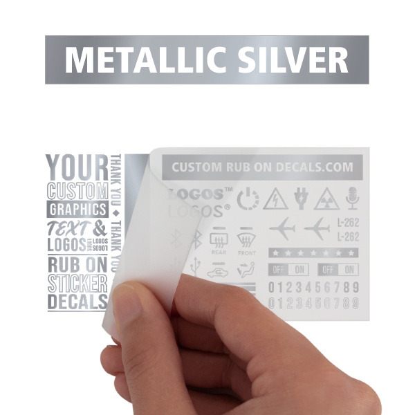 A person is holding a metallic silver rub on transfer.