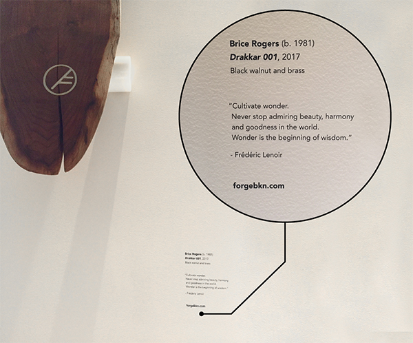 An image of a wooden skateboard with a custom rub down transfer hanging on a wall.