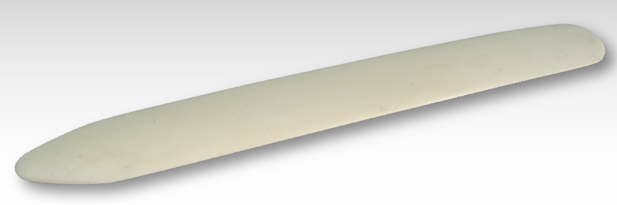 A white stone knife on a gray background featuring rub-down transfer. A white stone knife on a gray background featuring rub-down transfer.